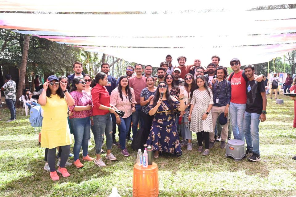 Corporate team posing under a fabric canopy during an outdoor offsite gathering