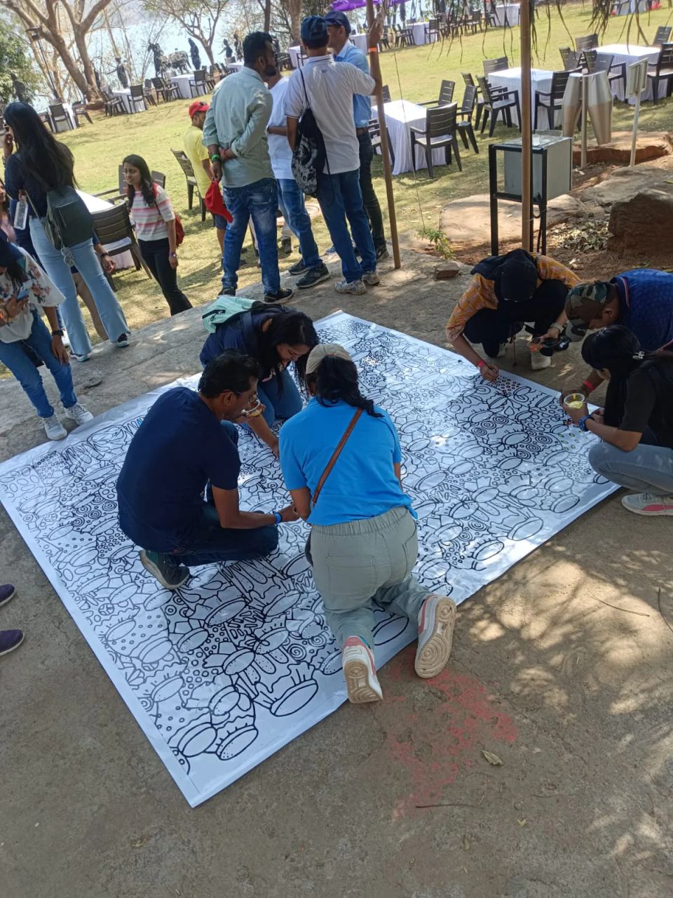 Guests colouring a large collaborative doodle canvas at an outdoor corporate team event