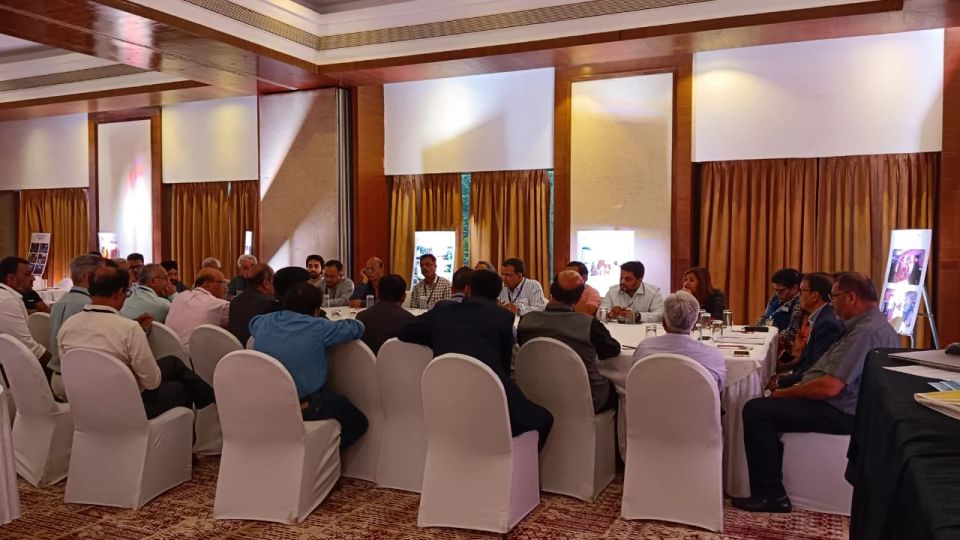 Professionals seated at a white-clothed roundtable discussion in a hotel conference hall